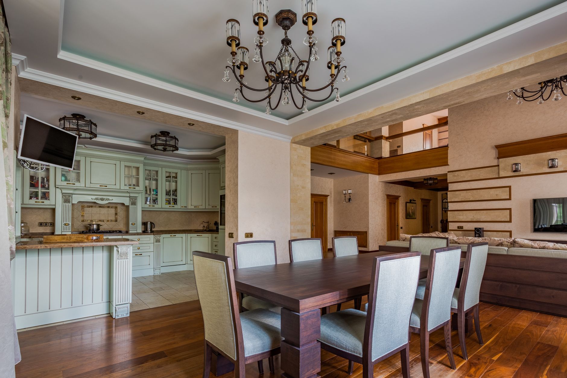 Spacious dining area with a classic chandelier next to a modern painted kitchen