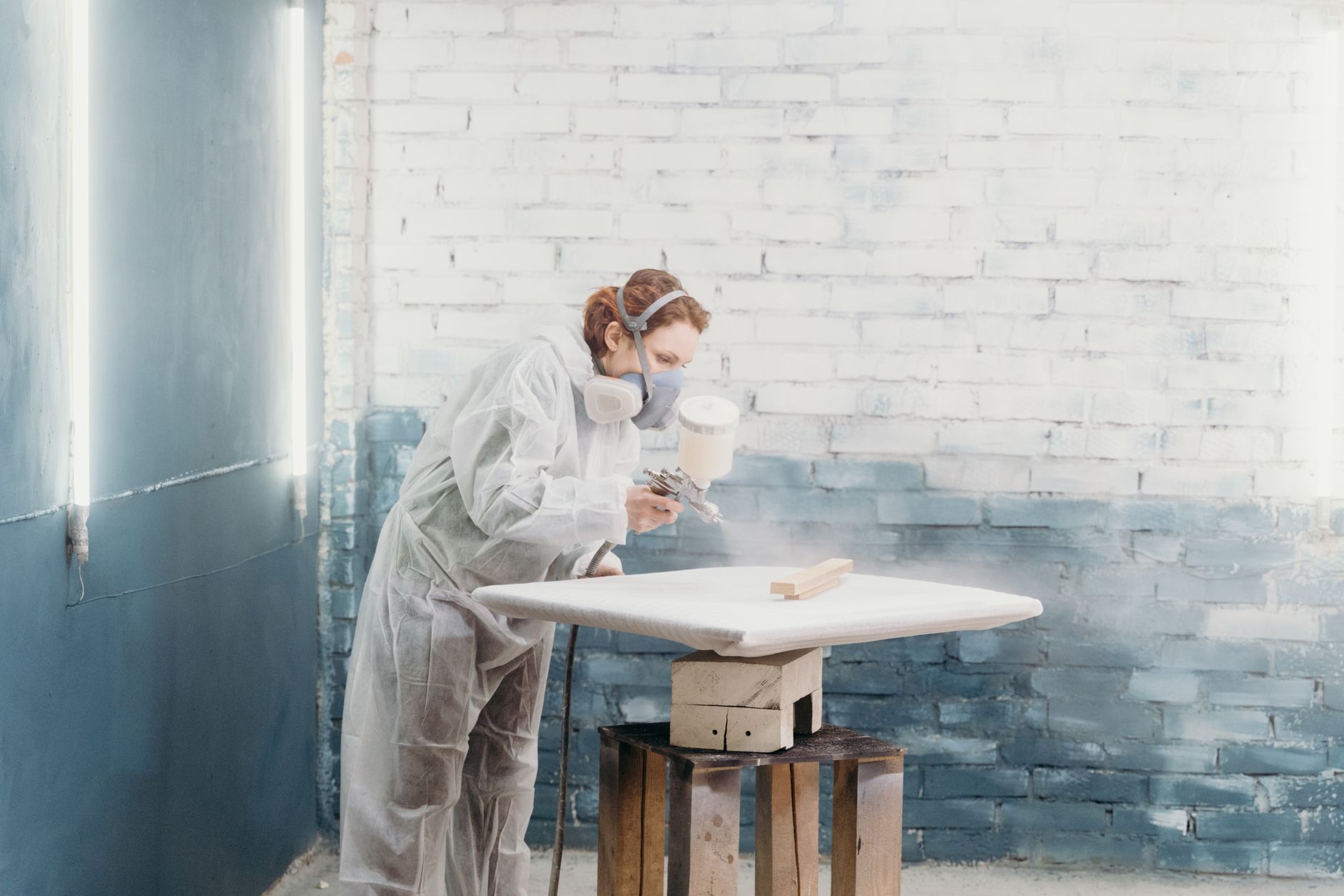 Painter in protective gear spraying a smooth, even finish, similar to the cabinet-grade process used for kitchen cabinet painting