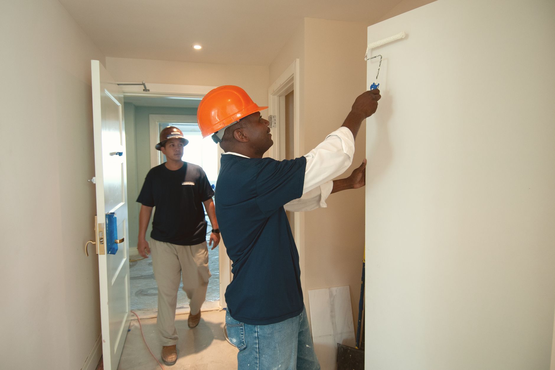 Two construction workers painting and renovating an interior, working as a team on a home improvement project
